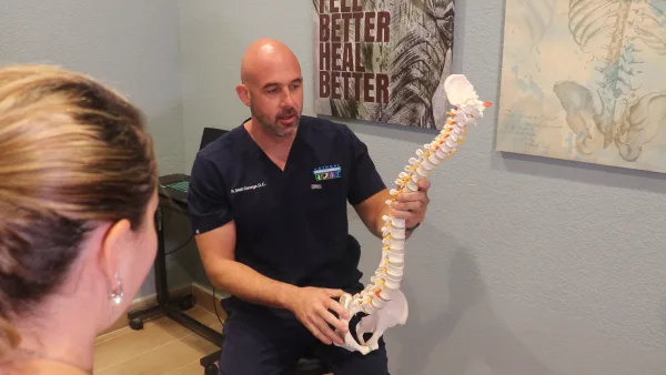 Dr. Matthew George of Anthony Medical & Chiropractic Center using a spine model to explain treatment to a patient