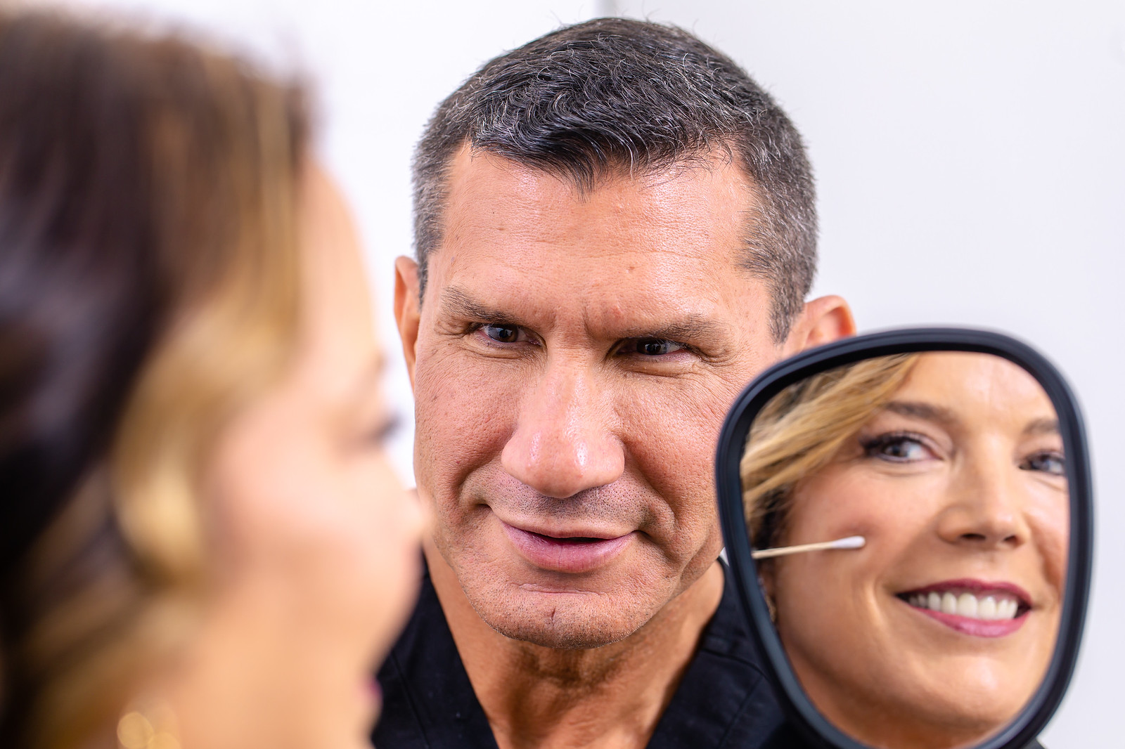 Dr. Philip J. Miller consulting with a patient reviewing facial rejuvenation results in a hand mirror at Gotham Plastic Surgery in Manhattan