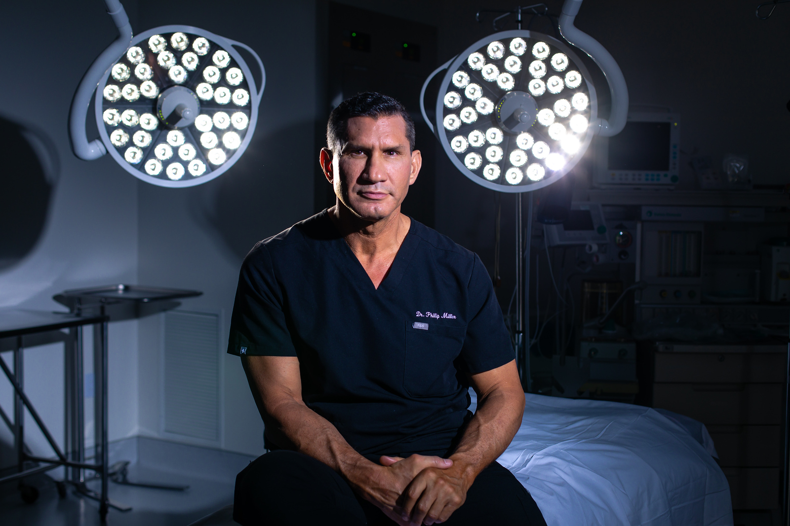Dr. Philip J. Miller seated beneath surgical lights in the operating suite at Gotham Plastic Surgery in Manhattan